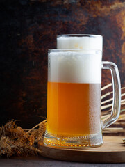 Two glasses of cold wheat beer in water drops close-up, wheat ears