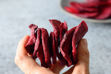 Vegetable beetroot chips in hand. Vegan snack. Close up. Healthy fast food.