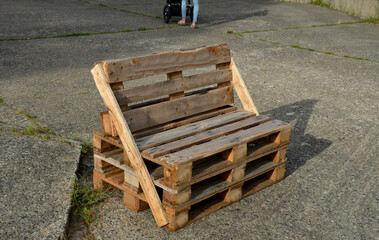 bench made of returnable pallets for goods. it has a back and seat made of wooden planks. stands on...