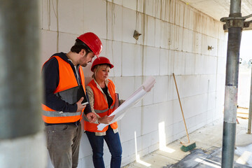 Architects team with construction drawing on the construction site