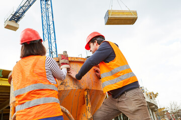 Construction workers at the cement mixer with lumber on the construction crane
