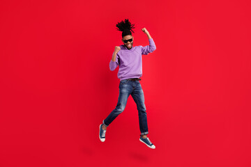 Full length body size photo man with dreadlocks gesuring like winner jumping up isolated vivid red color background
