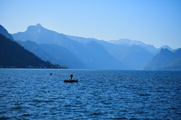 Ein Angler im Boot einsam auf einem See in den Bergen