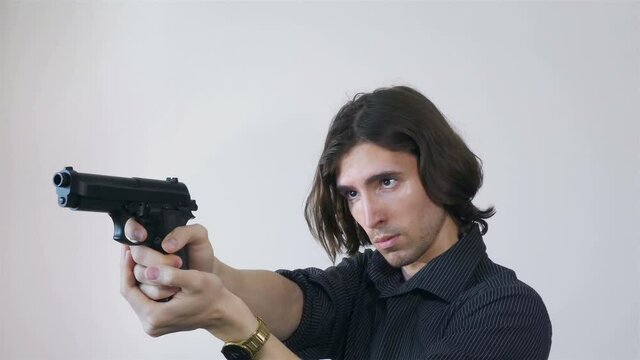 Young handsome man in dark shirt aiming the gun towards invisible target, 4k closeup, gold watches