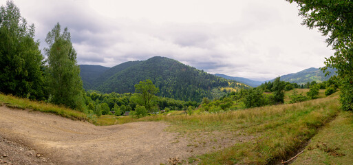 Fototapeta na wymiar Panorama of the Carpathian mountains in August landscape with grass, trees, sky