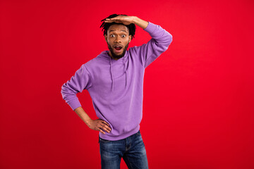 Fototapeta premium Photo portrait man with dreadlocks amazed looking far hand near forehead isolated vibrant red color background