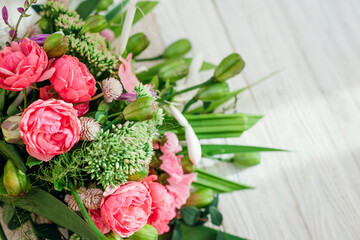 Bouquet of pink white green flowers arranged on wooden background. Roses, sedum, hosta, seed pods and grasses