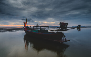 Fototapeta na wymiar Fishery wooden boat with sunset sky low lighting.