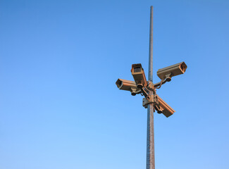 Column surveillance cameras on clear blue background, copy space