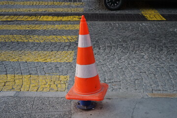 Lübecker Hütchen oder Verkehrsleitkegel auf einem Poller an einem gelben Zebrastreifen auf grauem...