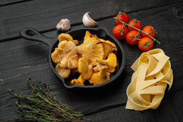 Obraz na płótnie Canvas Pasta ingredients with raw mushrooms chanterelles, on black wooden table background
