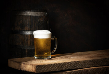 Beer barrel with beer glasses on a wooden table. Dark amber background.