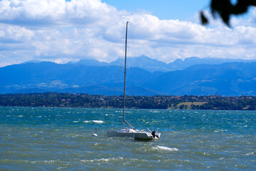 Lake Geneva on a sunny and windy summer day with sailing boat and European Alps in the background. Photo taken August 28th, 2021, Nyon, Switzerland.