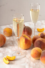 Vertical image of wineglasses and lot of fresh juicy peaches on the table.White wine with peaches