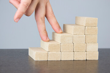 businesswoman's female fingers climb wooden blocks, the concept of business success