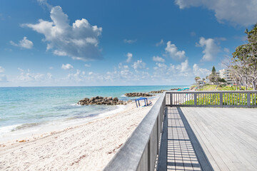 Landscape photograph of a large deck with railing overlooking the Atlantic Ocean at Deerfield Beach Florida under a cloudy blue sky. © Greg Kullman/Wirestock