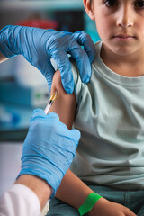 Child vaccination concept. Pediatrician injecting a vaccination dose in a child under 10 years of...