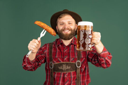 Portrait of bearded man, waiter in traditional Bavarian costume with one liter of dark beer isolated over green background. Oktoberfest, festival, traditions concept
