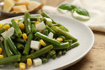 Delicious salad with green beans, corn and cheese on wooden table, closeup