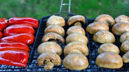 Delicious champignons and juicy red pepper  on the grill on the coals  close-up. Picnic food outdoor cooking. 