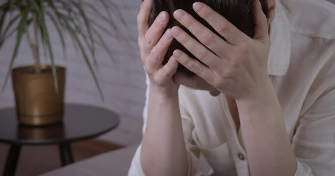 Overstress woman. A view of sad overstressed woman sitting on the sofa in the room.