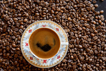 coffee beans in the background and a cup of frothy turkish coffee on top. Selective Focus.