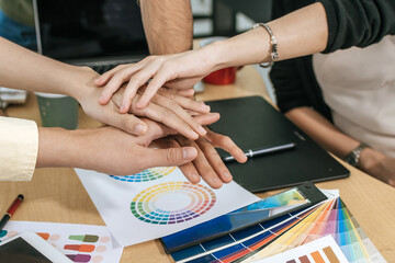 group of colleagues young business hand join together for successful business meeting with color sample chart on desk in meeting room at office, interior design, architect, graphic designer concept