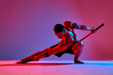 athlete men silhouette with stick training karate using sports tool in studio on colorfull lights...
