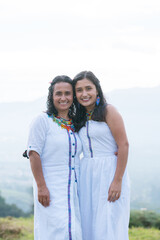 two Colombian women smiling, wearing white clothes. women of an indigenous community smiling. present life, Colombian ethnicity in nature