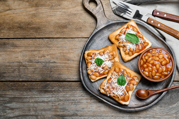 Toasts with delicious canned beans on wooden table, flat lay. Space for text