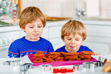 Two little preschool boys baking gingerbread cookies. Happy siblings, children in xmas sweaters....
