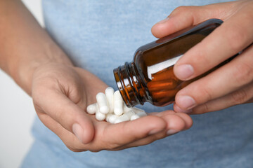 Man with amino acids pills on light background, closeup