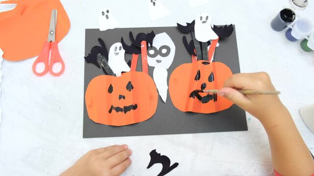 Child making pumpkins for the holiday of halloween. Funny crafts from paper. Halloween decor. Handicraft. The concept for Halloween. DIY. Children's art project, a craft for children.