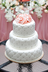 a multi level white wedding cake and pink flowers on top. Big cake.