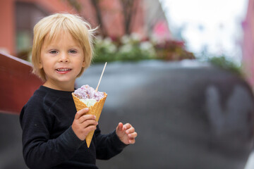 Fototapeta premium Cute blond child with black shirt, eating churros on the street in the city of Stockhlom, sweet desert sold on every corner