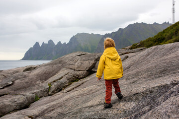Child, having fun in Tungeneset, Senja, Norway, jumping over big puddle