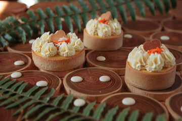 dessert, cheesecake with mango and passion fruit in the form of brownies with mousse on top. Decorated with cookies in the form of a heart. On a wooden table in a white plate