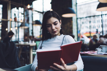 Focused woman reading notebook in cafe