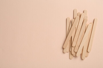 Wooden waxing spatulas on beige background, flat lay. Space for text