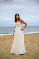 Fototapeta na wymiar Glückliche junge Frau im Hochzeitskleid am Meer 