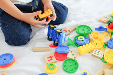 colorful plastic toys on bed with blurred child in the background , Select focus