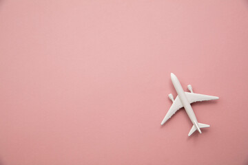 white toy airplane on a pastel pink background. Flight travel background with copy space