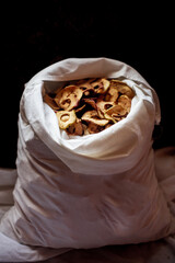 Dried apples in rings in a white bag on a dark background. Stocks for the winter. A healthy snack with vitamins