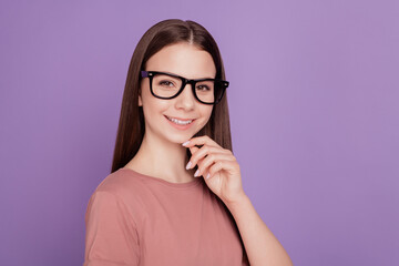 Portrait of young genius creative teen woman wearing ing glasses touching chin hands against violet background