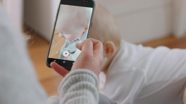 mother taking photo of baby using smartphone enjoying photographing cute toddler sharing motherhood lifestyle on social media