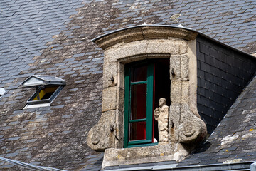 Offenes altes Dachfenster, Dachgaube mit Heiligenfigur aus Stein in Ville Close, historische...