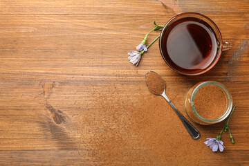 Cup of delicious chicory drink, powder and flowers on wooden table, flat lay. Space for text