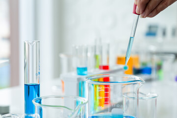 Scientist with a pipette analyzes dropping colored liquid to extract the DNA and molecules in the test tubes for reaction testing in chemical laboratory.