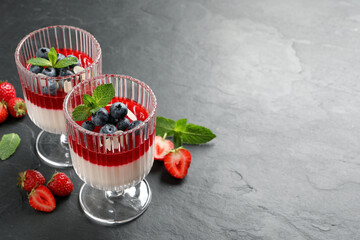 Delicious panna cotta with fruit coulis and fresh berries on dark grey table. Space for text