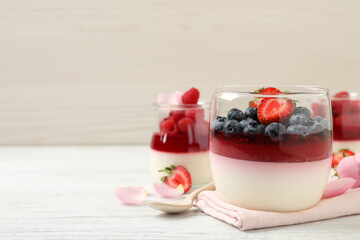Delicious panna cotta with berries on white wooden table. Space for text